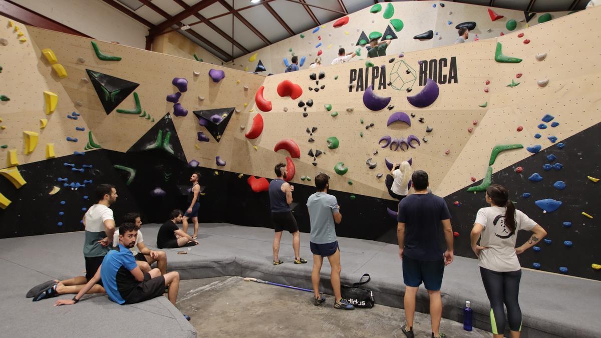 Los aficionados reunidos en la colchoneta mientras descansan y se preparan para arrancar la escalada.