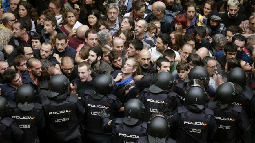 Agentes antidisturbios de la Policía Nacional forman un cordón de seguridad en los alrededores del colegio Ramón Llull de Barcelona