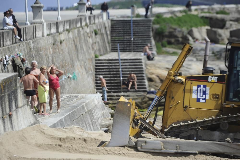 Las máquinas extienden la arena en la playa de Riazor.