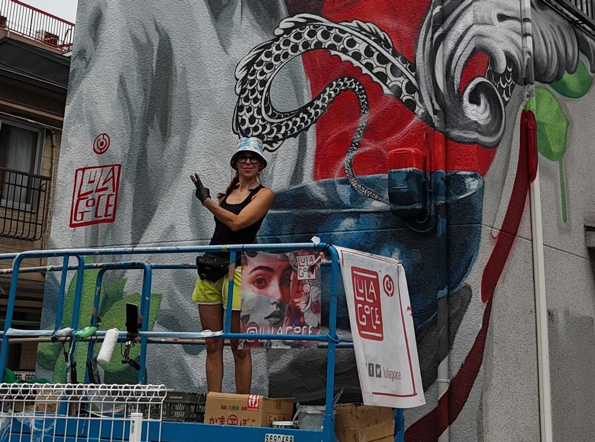 Imagen de la artista Lula Goce junto a uno de sus murales.