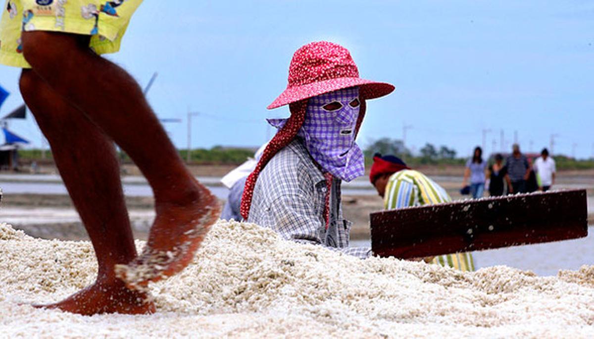Un treballador tailandès recol·lecta sal en un poble pròxim a Bagkok.