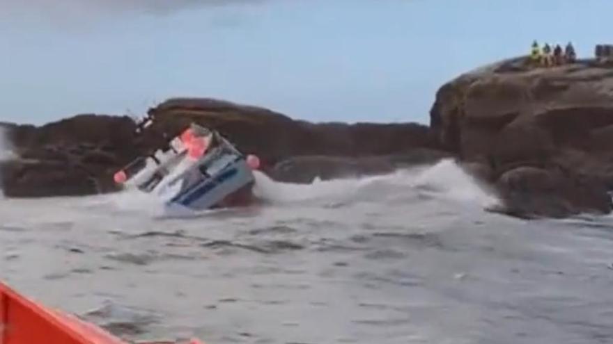 El barco, contra las rocas, y los tripulantes a la derecha, a salvo. Rescate en Muros de cuatro marineros tras el naufragio de su barco. 31 octubre 2023. Salvamento Marítimo