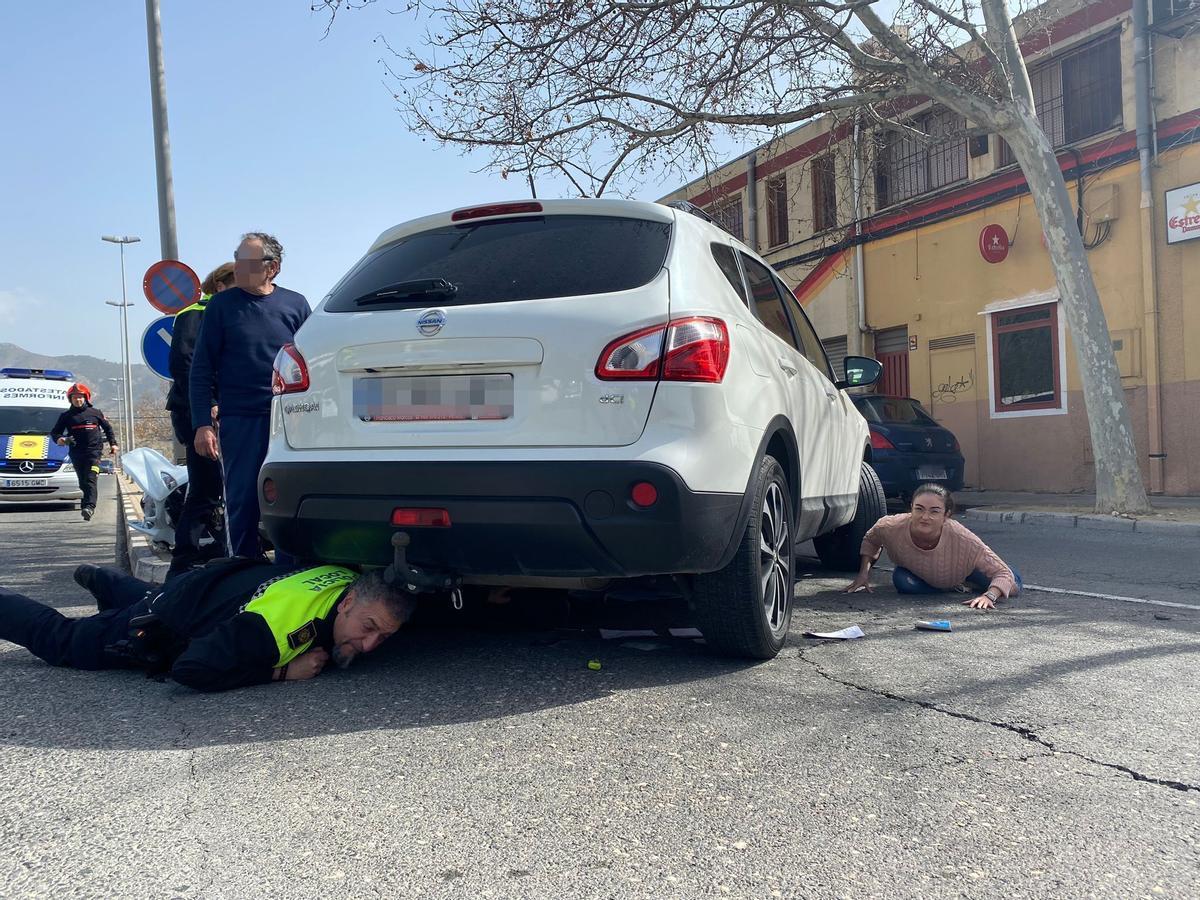 El momento en el que un agente de la Policía Local y una enfermera auxilian al herido atrapado debajo del coche.