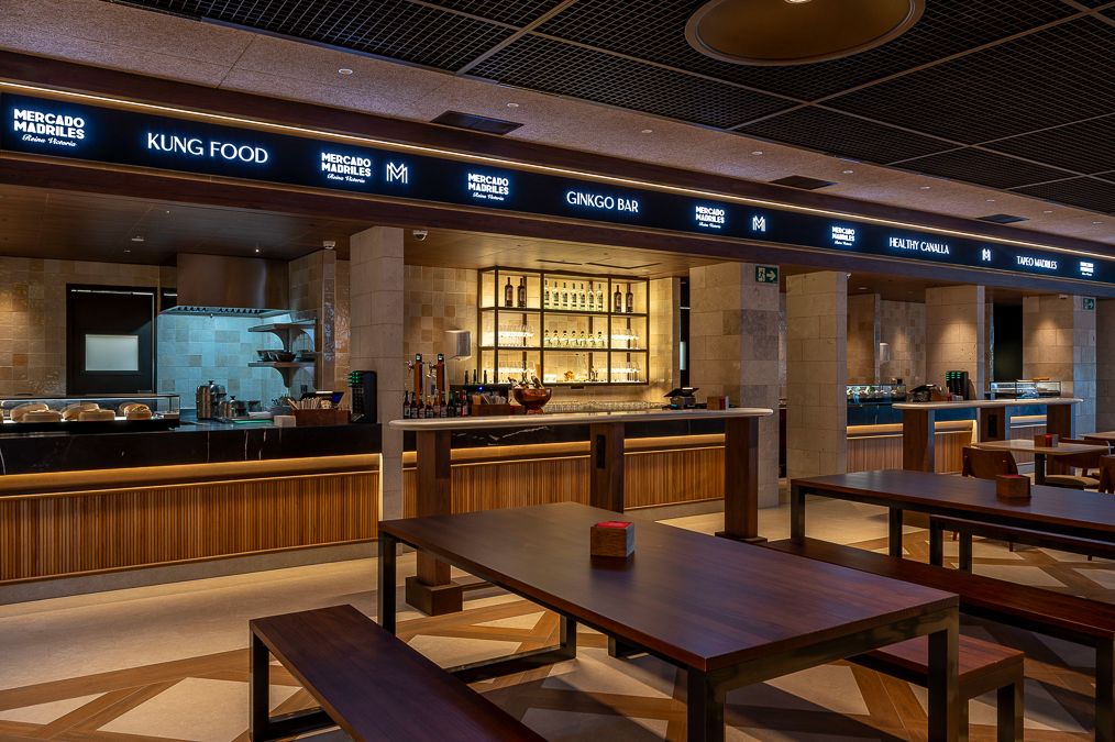Interior del Mercado Madriles Reina Victoria, un espacio gastronómico que combina puestos especializados, diseño contemporáneo y ambiente social en pleno barrio de Chamberí.