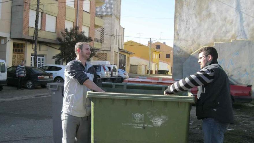 Dos jóvenes depositan basura en un contenedor instalado en una calle de Santibáñez de Vidriales