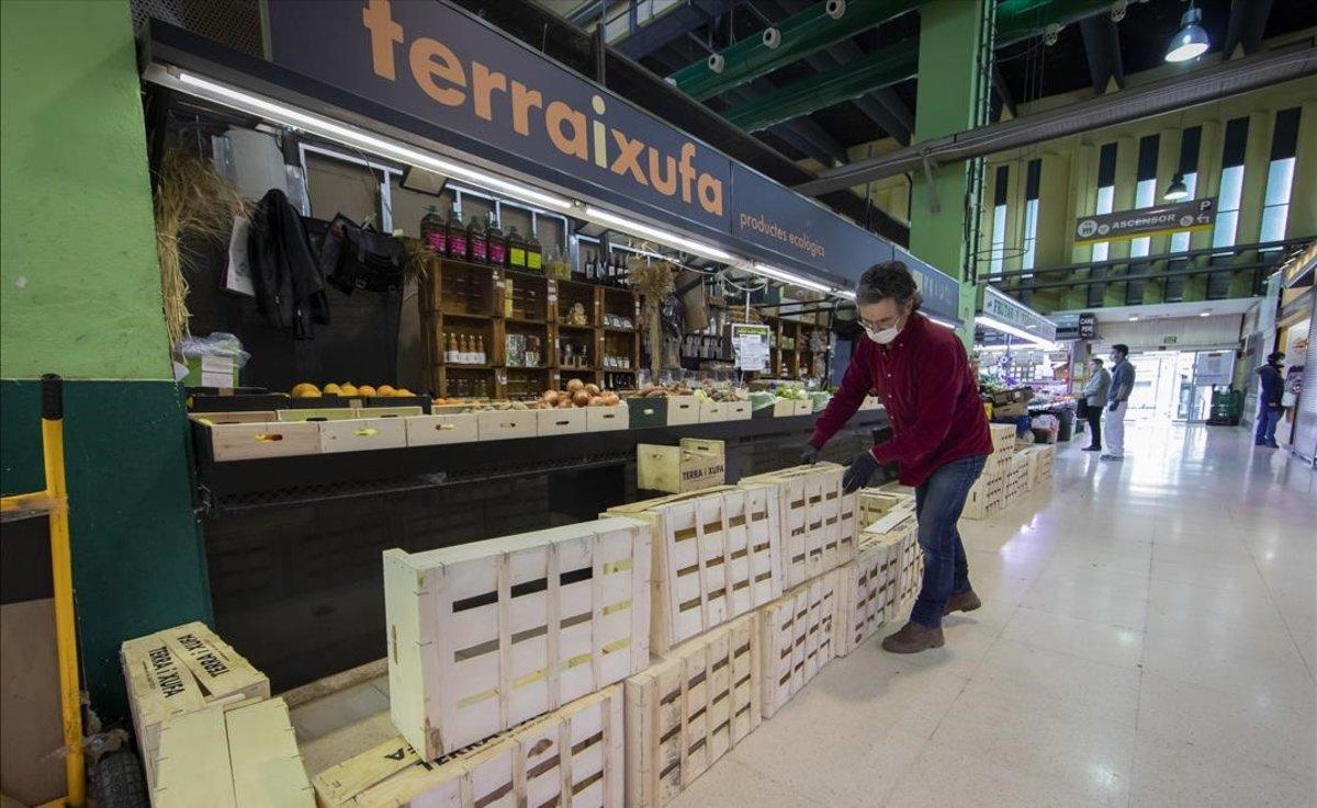 Emilio coloca una barrera de cajas ante su parada en el mercado en Valencia.