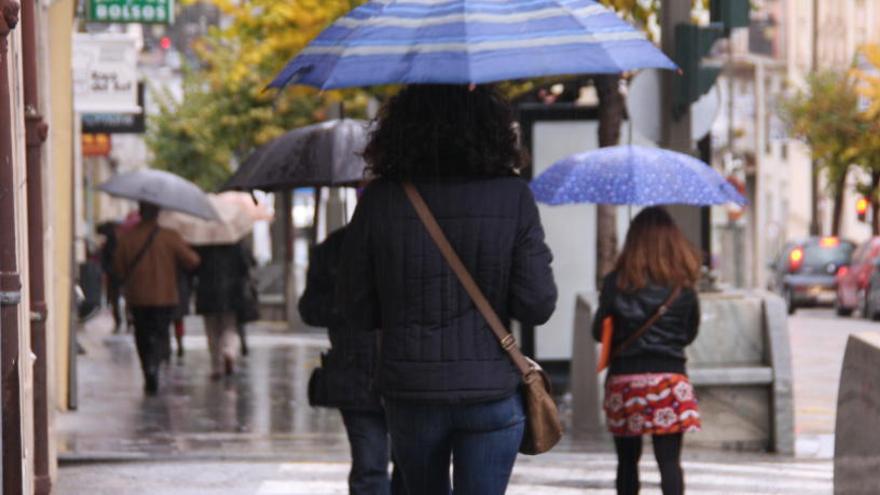 Viandantes protegiéndose de la lluvia con paraguas en Alcoy