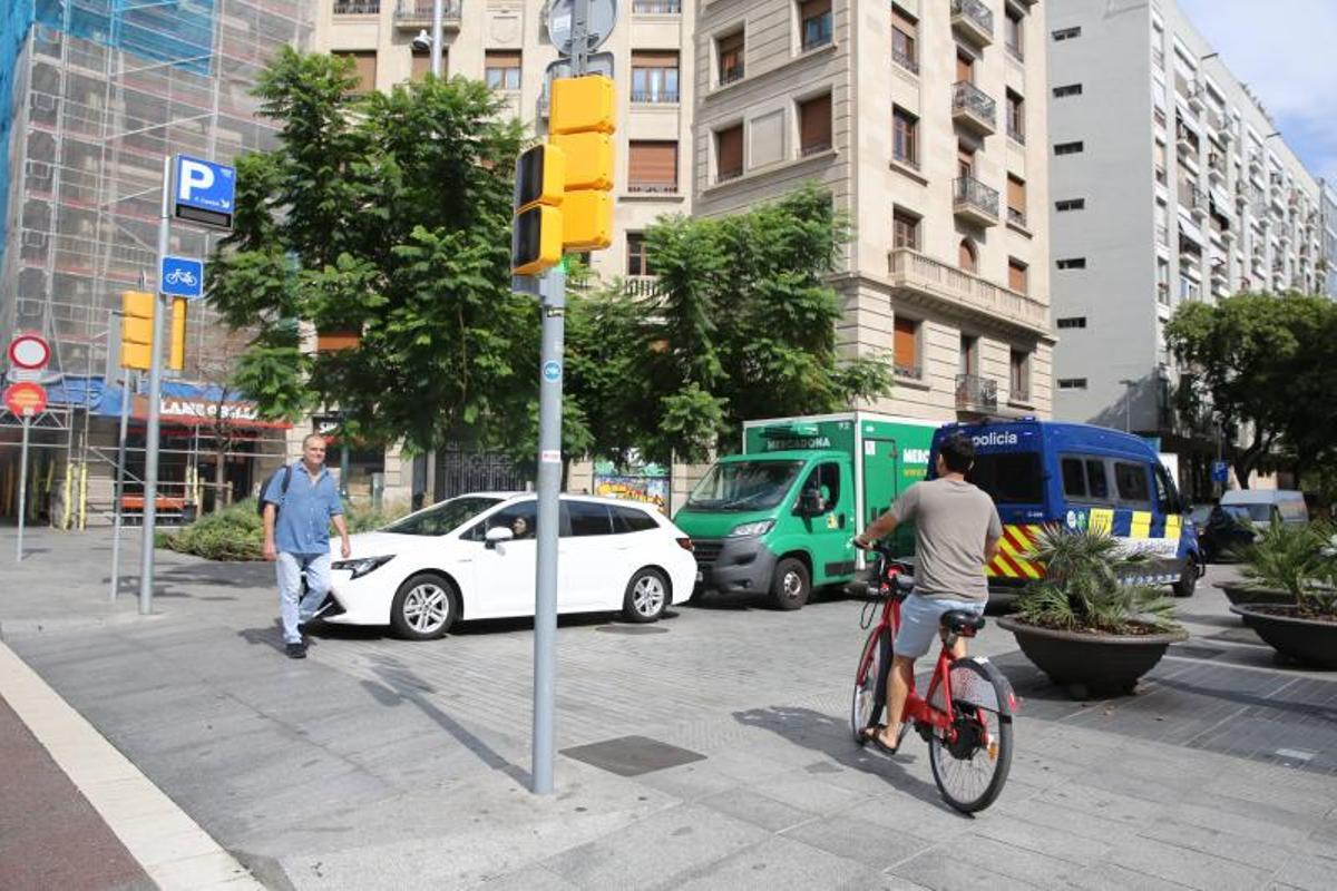 Un peatón cruza por la plataforma única cerca de las jardineras colocadas en verano para impedir que los coches salgan del párking de Francesc Cambó por el paso de peatones.