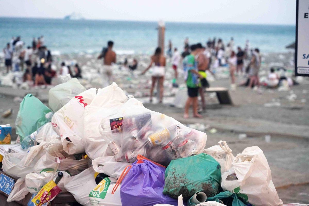 Varios operarios de la empresa de limpieza de Limasam, recogen los residuos de la playa de La Malagueta, tras la Noche de San Juan en Málaga 2025