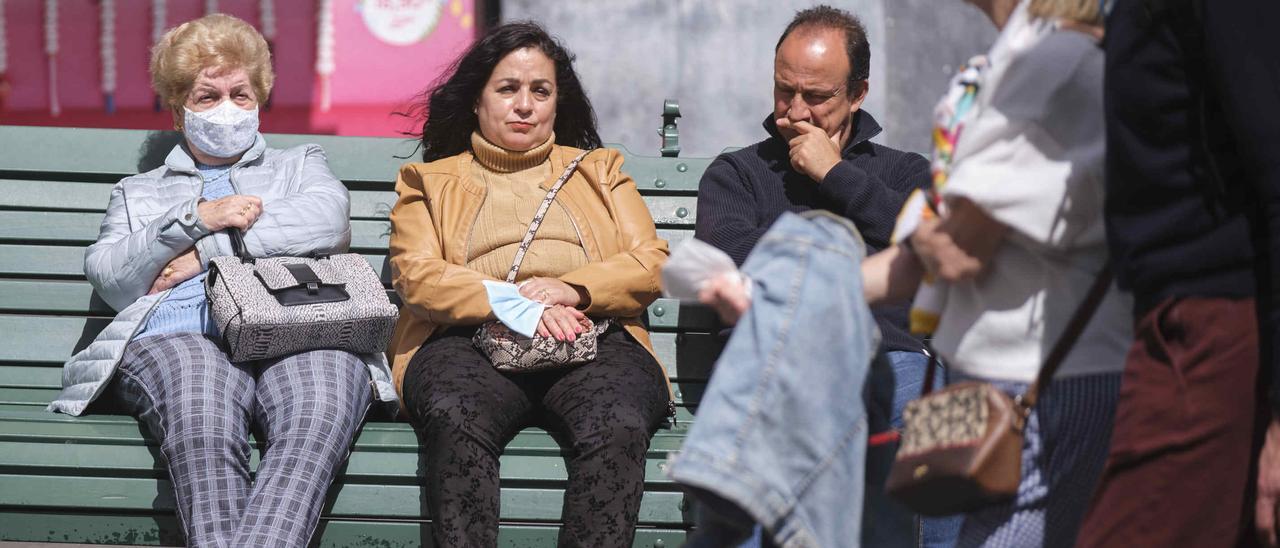 Varias personas descansan en un banco de la capital tinerfeña.