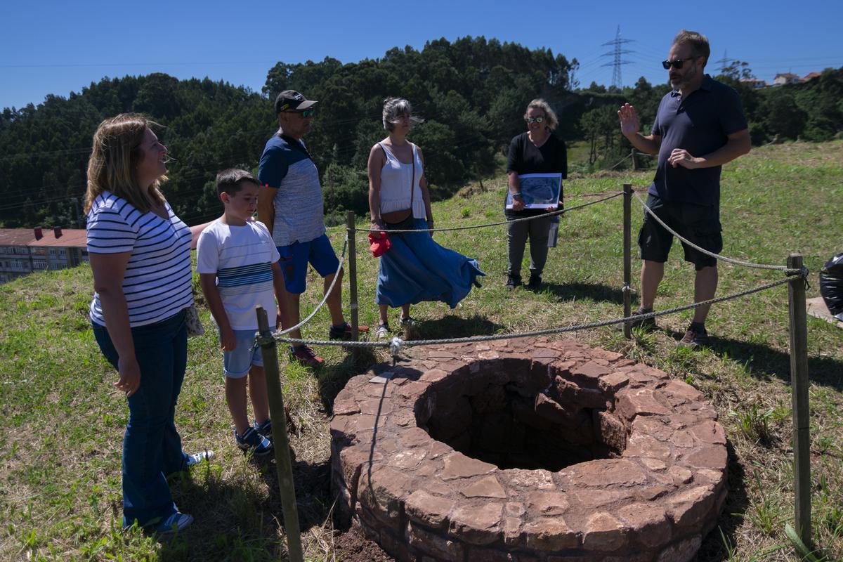 Un grupo de visitantes observan el pozo del castillo de Gauzón.