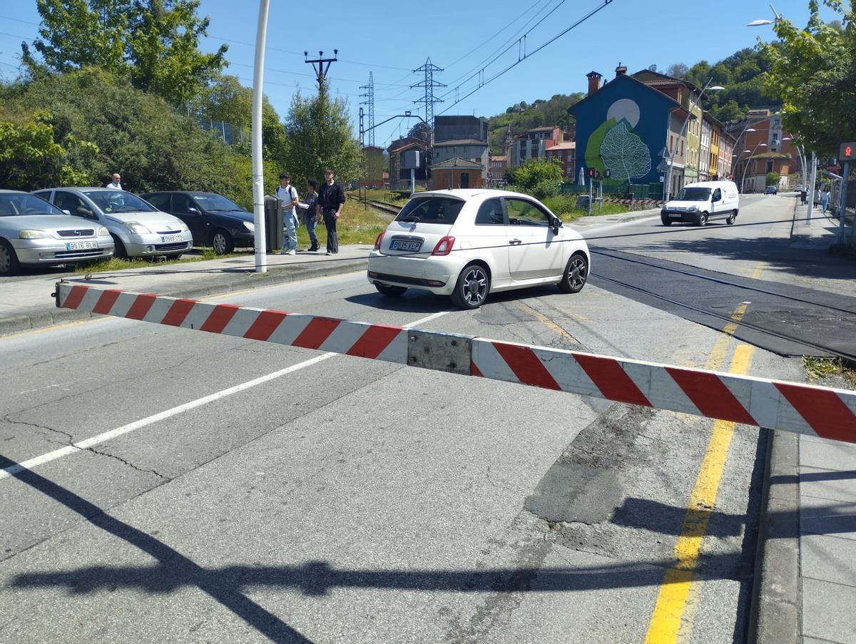 Coches pasando con las barreras bajadas en el paso a nivel de Ciaño.