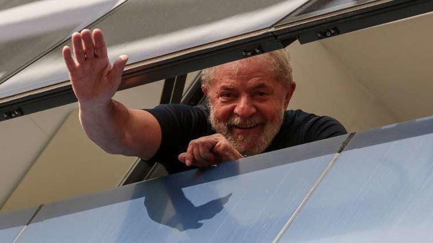 El expresidente brasileño Lula da Silva saluda a los militantes de su sindicato desde el interior del edificio. // AFP