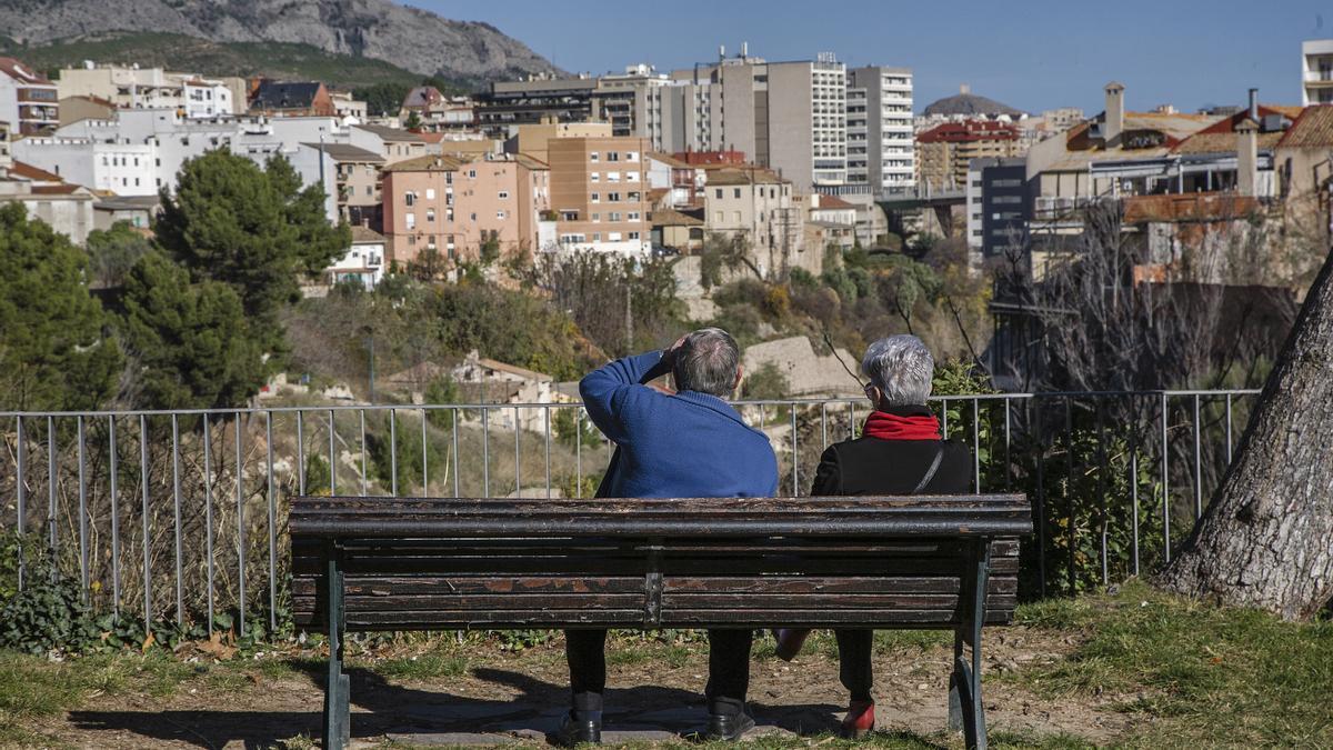 Dos personas mayores sentadas en un banco en el casco urbano de Alcoy.
