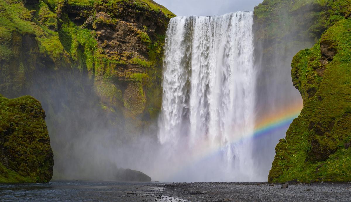 El espectacular fenómeno de los arcoíris en la Cascada Gullfoss ocurre cuando la intensa luz solar atraviesa la niebla y las minúsculas gotas de agua en suspensión generadas por sus dos impresionantes caídas