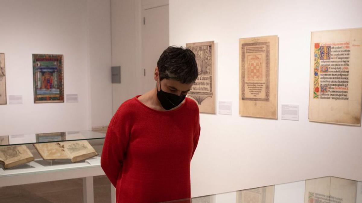 Una mujer contempla uno de los libro antiguos expuestos. | Emilio Fraile