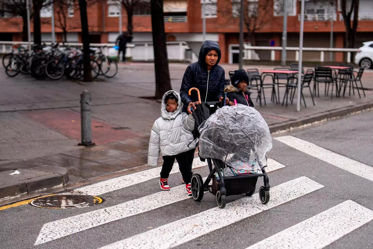 Una madre pasea con sus tres hijos en el barrio del Remei de Vic.