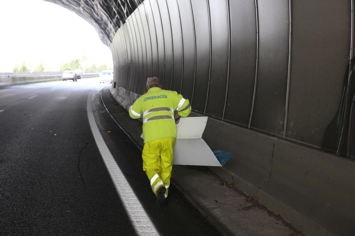 Operario de Carreteras recoge una de la planchas que voló del túnel de Montealegre en la Autovía en Domaio.
