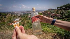 Zona de la carretera de les Aigües donde, según denuncian los vecinos, se celebran botellones durante la noche. En la imagen, una botella de vidrio abandonada junto a numerosas colillas en un área donde, aseguran, algunas personas también acampan y dejan residuos que incrementan el riesgo de incendio en el parque natural de Collserola. Barcelona, 14 de julio de 2026. AUTOR: Manu Mitru | EPC