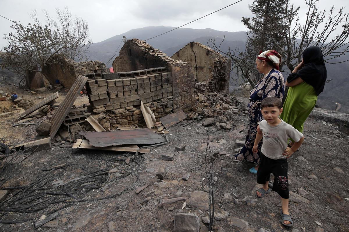 Oeud Das (Algeria), 25/07/2023.- An elderly woman with her grandchild looks at her burned house in the village of de Oeud Das in Bejaia east of Algiers, Algeria, 25 July 2023. The Algerian Ministry of the Interior announced at least 34 people died, including 24 civilians and 10 members of the National Army and 26 people are injured in multiple forest fires across the country. (Argel) EFE/EPA/STR