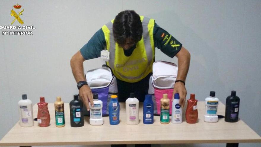 Un agente de la Guardia Civil con los botes de cosméticos que contenían la cocaína líquida