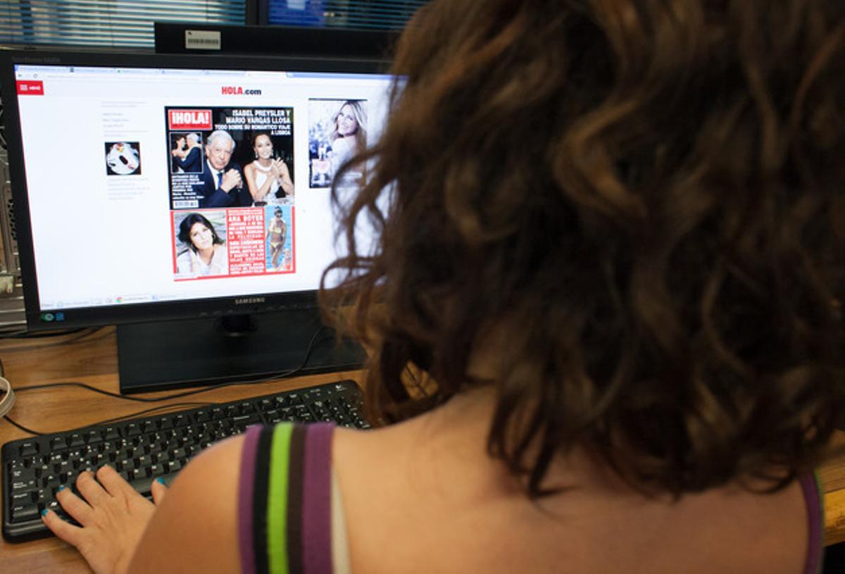 Una noia mira la portada de la revista ’¡Hola!’ a través d’un ordinador.