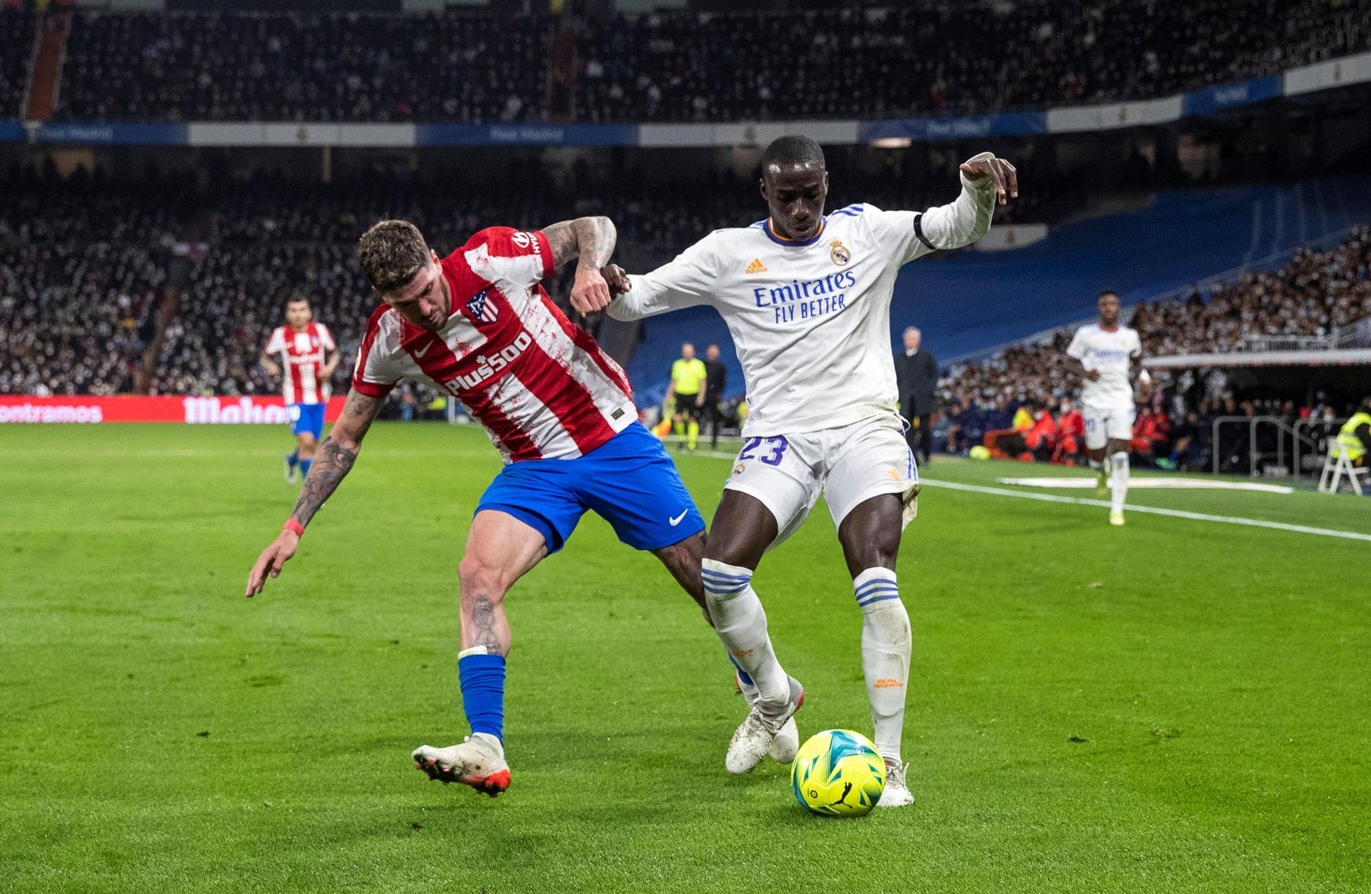 El defensa francés del Real Madrid, Ferland Mendy (d), disputa el balón ante el centrocampista argentino del Atlético de Madrid, Rodrigo de Paul, durante el encuentro correspondiente a la decimosexta jornada de primera división que han disputado este domingo frente al Real Madrid en el estadio Santiago Bernabéu.