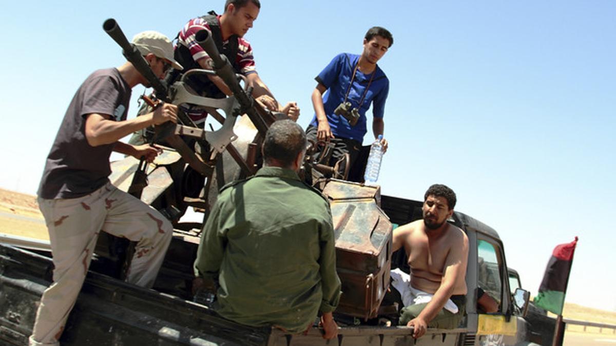 Rebeldes libios custodian a un prisionero gadafista, a la derecha, el lunes, a unos 130 kilómetros de Sirte.