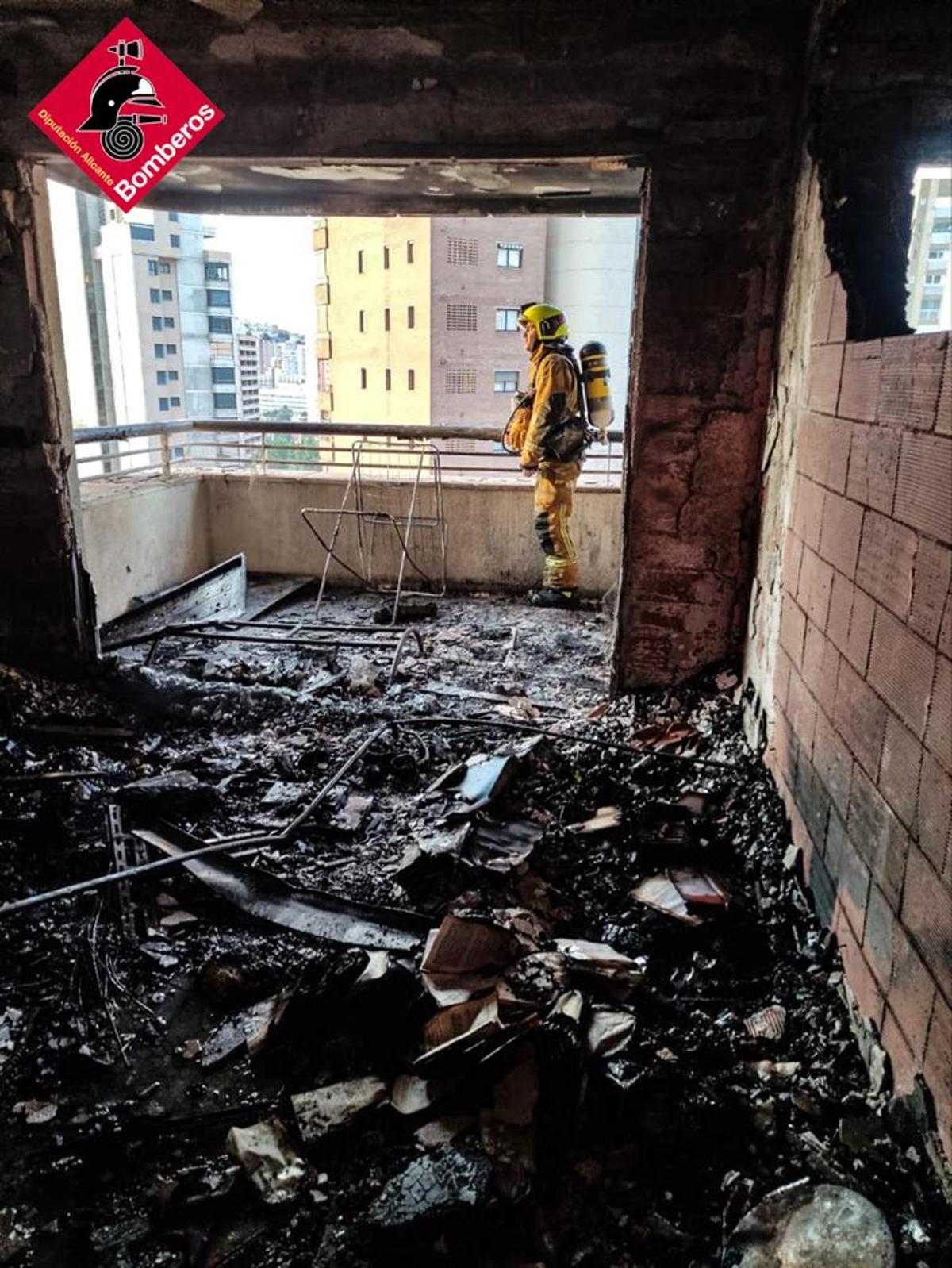 Un bombero trabaja en las labores de extinción del fuego en el piso calcinado donde se origino el incendio.