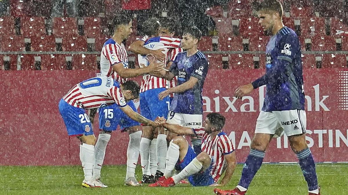 Els jugadors del Girona s’abracen, atuïts sota la pluja, després del xiulet final de l’àrbitre. | MARC MARTÍ