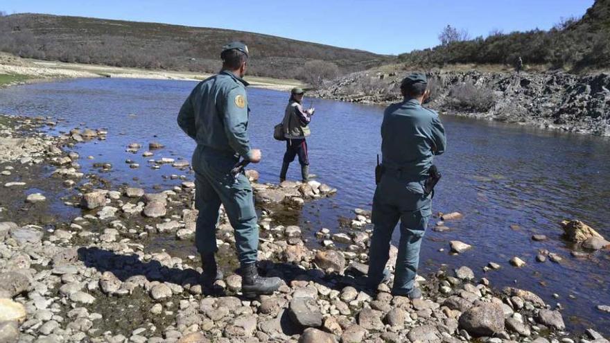 Dos agentes del Seprona observan los lances de un pescador en el Tera de Puebla.