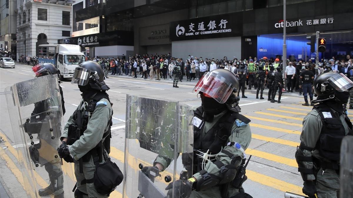 Policía antidisturbios vigila a manifestantes en el distrito financiero de Hong Kong.