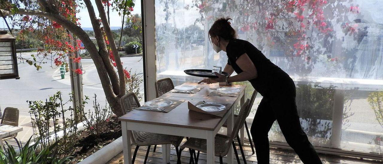 Una camarera prepara una mesa en una terraza de un restaurante de Sant Francesc.