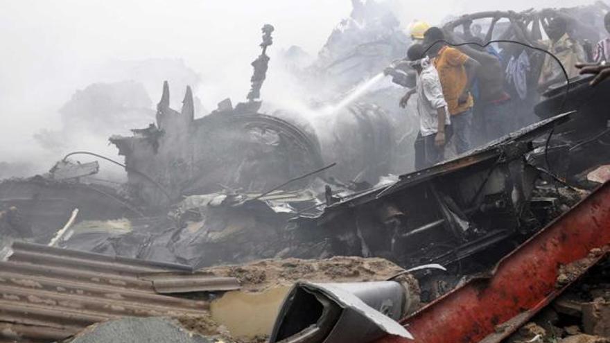 Vecinos de la barriada tratan de apagar el fuego del avión siniestrado.