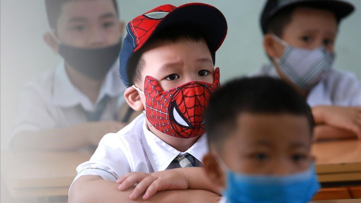 Alumnos con máscaras durante el primer día del nuevo año escolar, en la escuela primaria Phuc Dien, en Hanoi,  Vietnam.