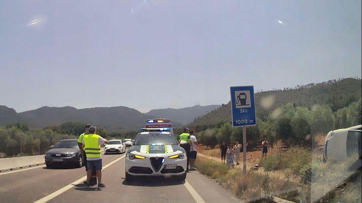 El coche accidentado, a la derecha de la vía, con la Guardia Civil y una ambulancia asistiendo.