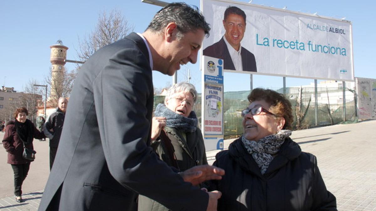 Xavier Garcia Albiol habla con unas vecinas de Badalona ante uno de los carteles de precampaña del PP en Badalona.