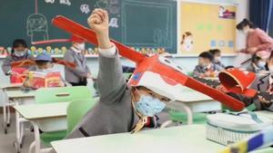 Los niños chinos aprenden distancia social usando sombreros con alas.