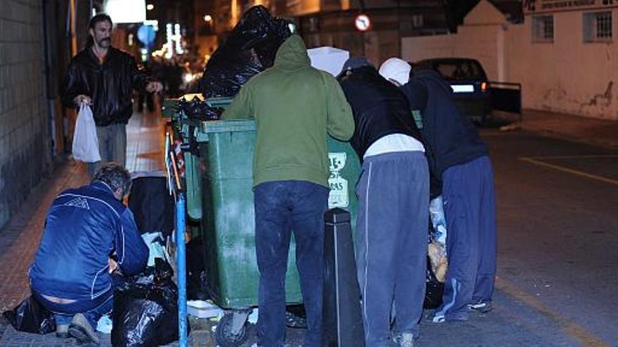 Un grupo de personas busca los alimentos que dejan los supermercados en una calle del casco urbano de Torrevieja en una imagen del jueves.