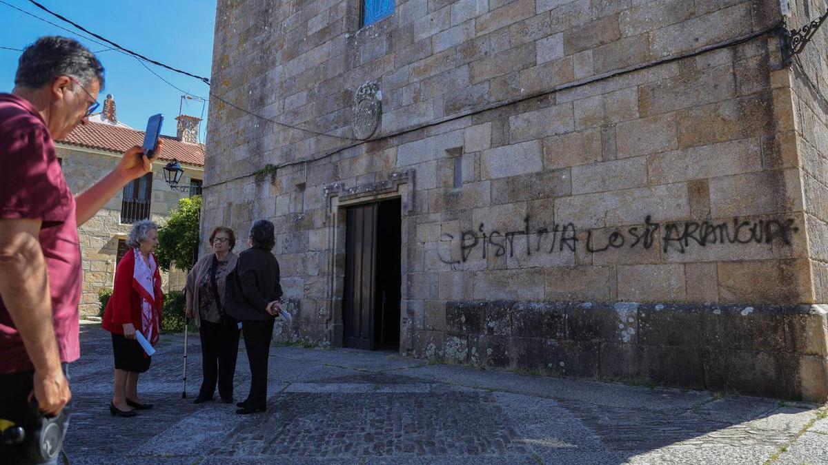 Un hombre toma una fotografía a la pintada de San Benito de Fefiñáns.
