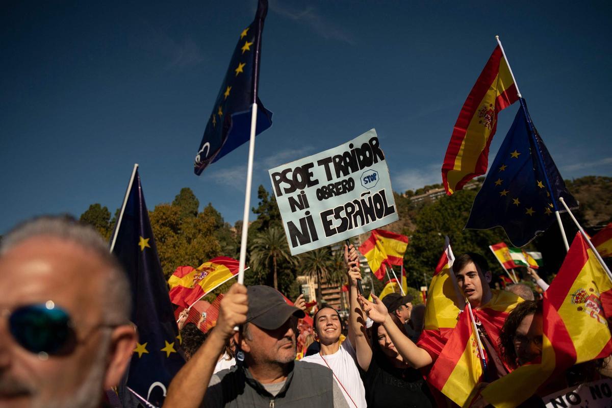 Los manifestantes marchan con una bandera gigante en Málaga durante una protesta convocada por la oposición de derecha contra un proyecto de ley de amnistía para las personas involucradas en el fallido intento de independencia de Catalunya de 2017, el 12 de noviembre de 2023.