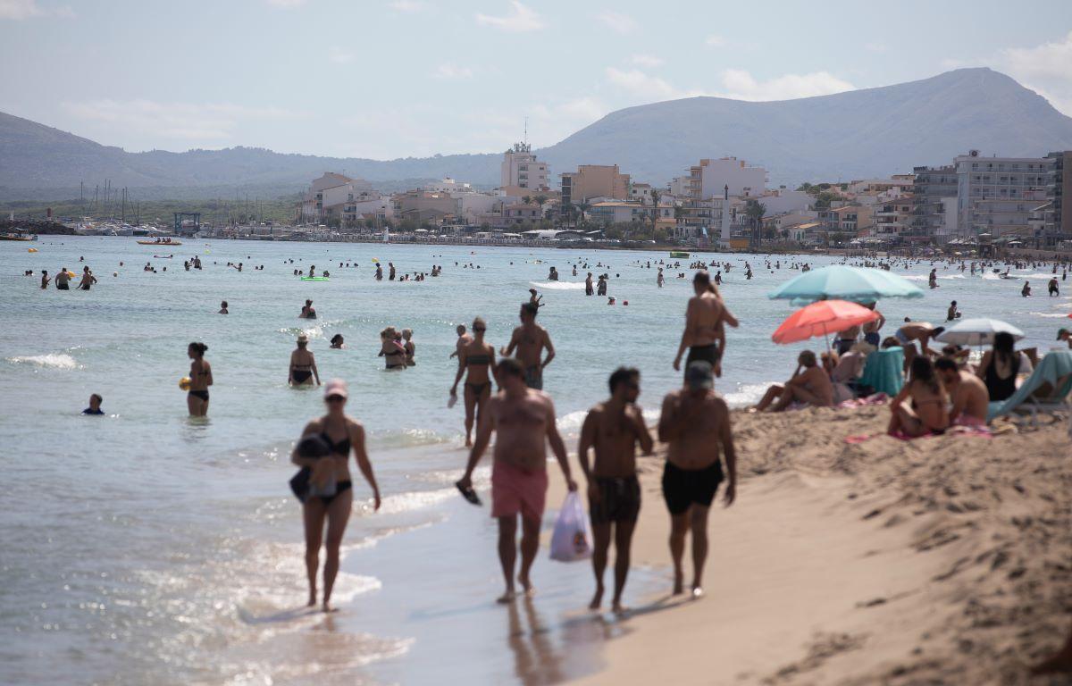 Menschen genießen das sonnige Wetter am Strand Playa de Muro an der Nordküste der Insel Mallorca.