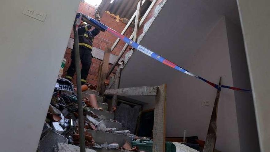 Un bombero trabajando en la casa para asegurar el techo. // G.S.