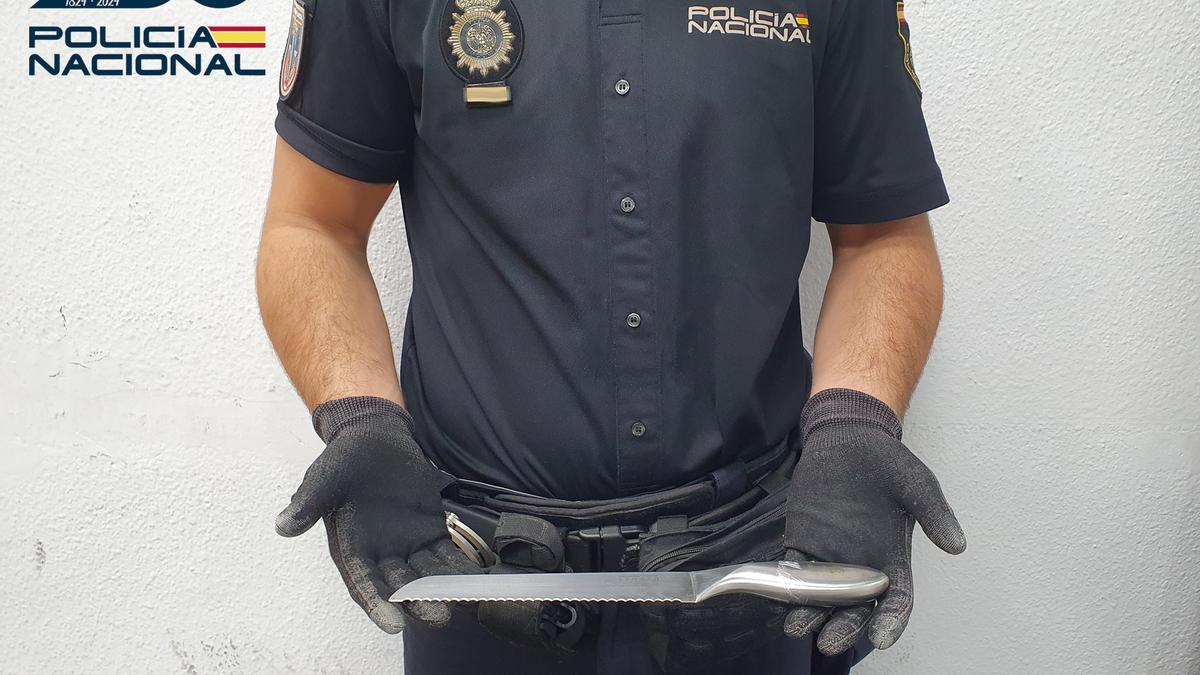 Un policía nacional sostiene el cuchillo intervenido al hombre con el que amenazó a la mujer.