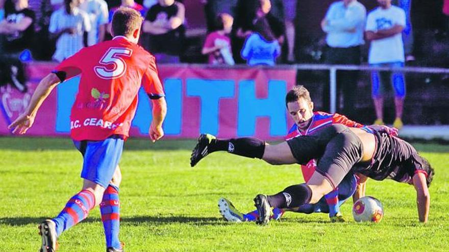 Dos jugadores caen al suelo en plena disputa por el balón.