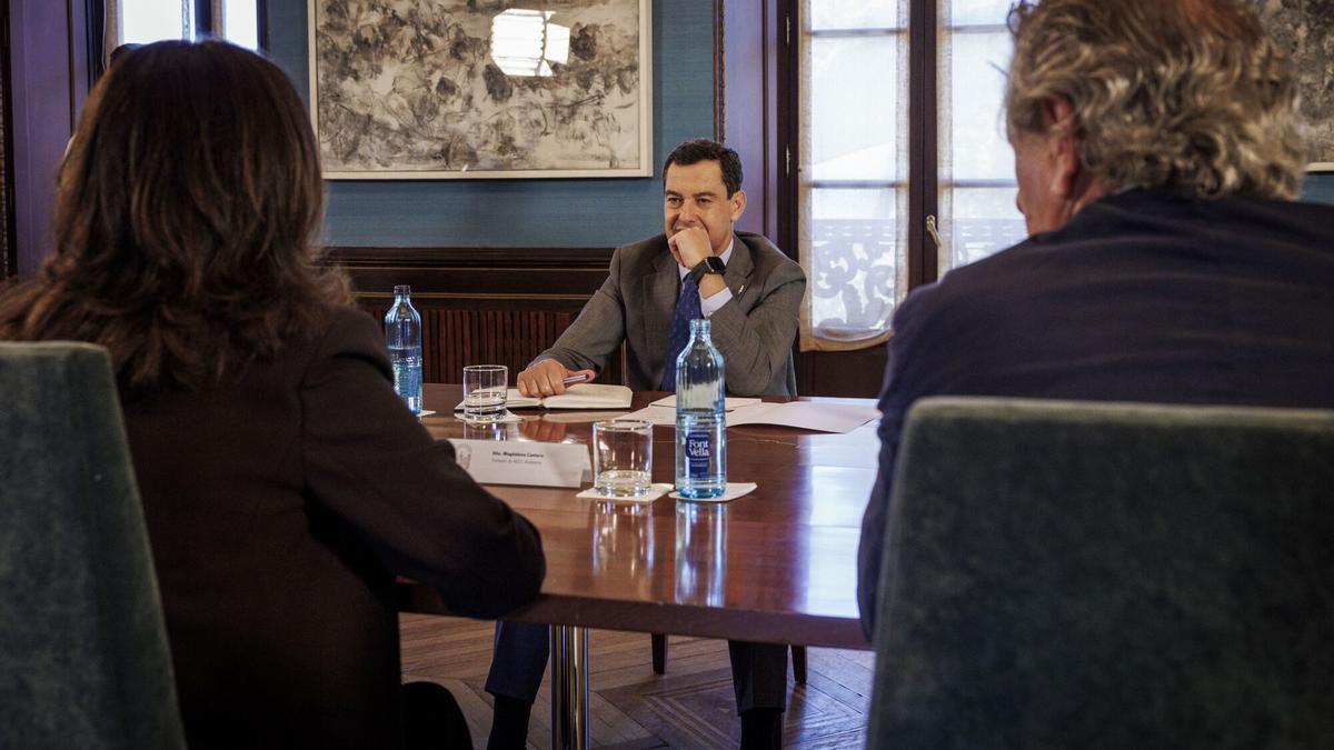 El presidente de la Junta de Andalucía, Juanma Moreno (c), y la portavoz de la Asociación Española Contra el Cáncer (AECC) en Andalucía, Magdalena Cantero (i), junto a miembros de su directiva.