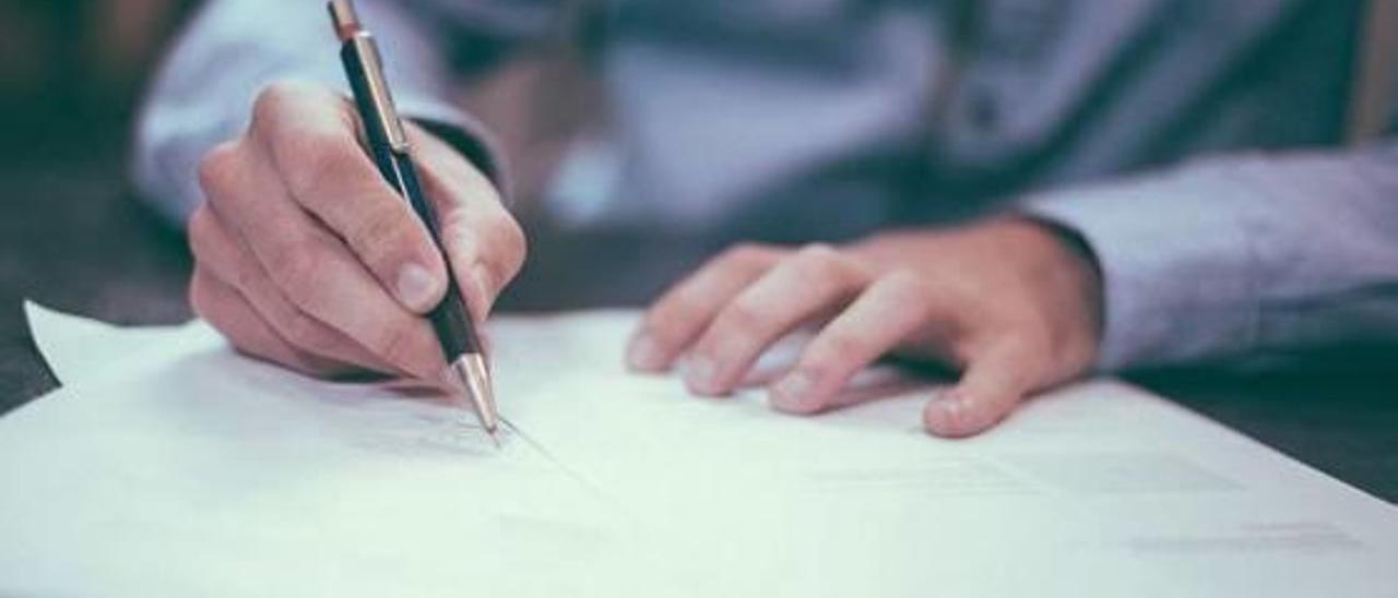 Una persona firmando un documento en una notaría.