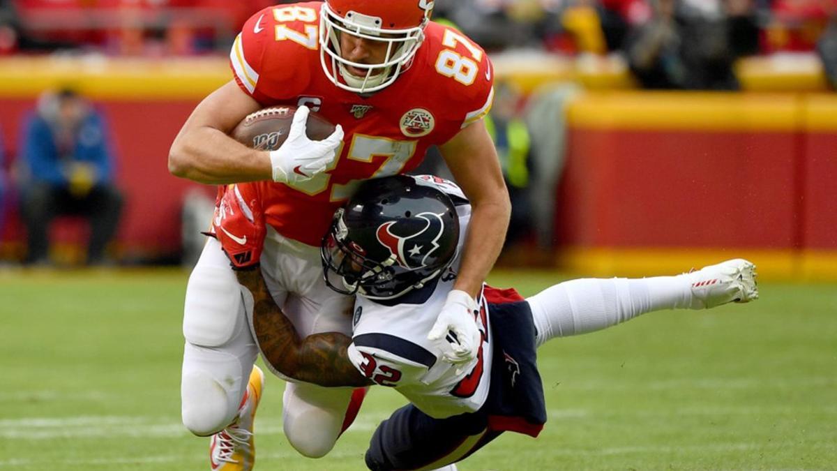 Travis Kelce # 87 de los Kansas City Chiefs es abordado por Lonnie Johnson # 32 de los Houston Texans durante el partido de desempate divisional de la AFC en el Arrowhead Stadium.