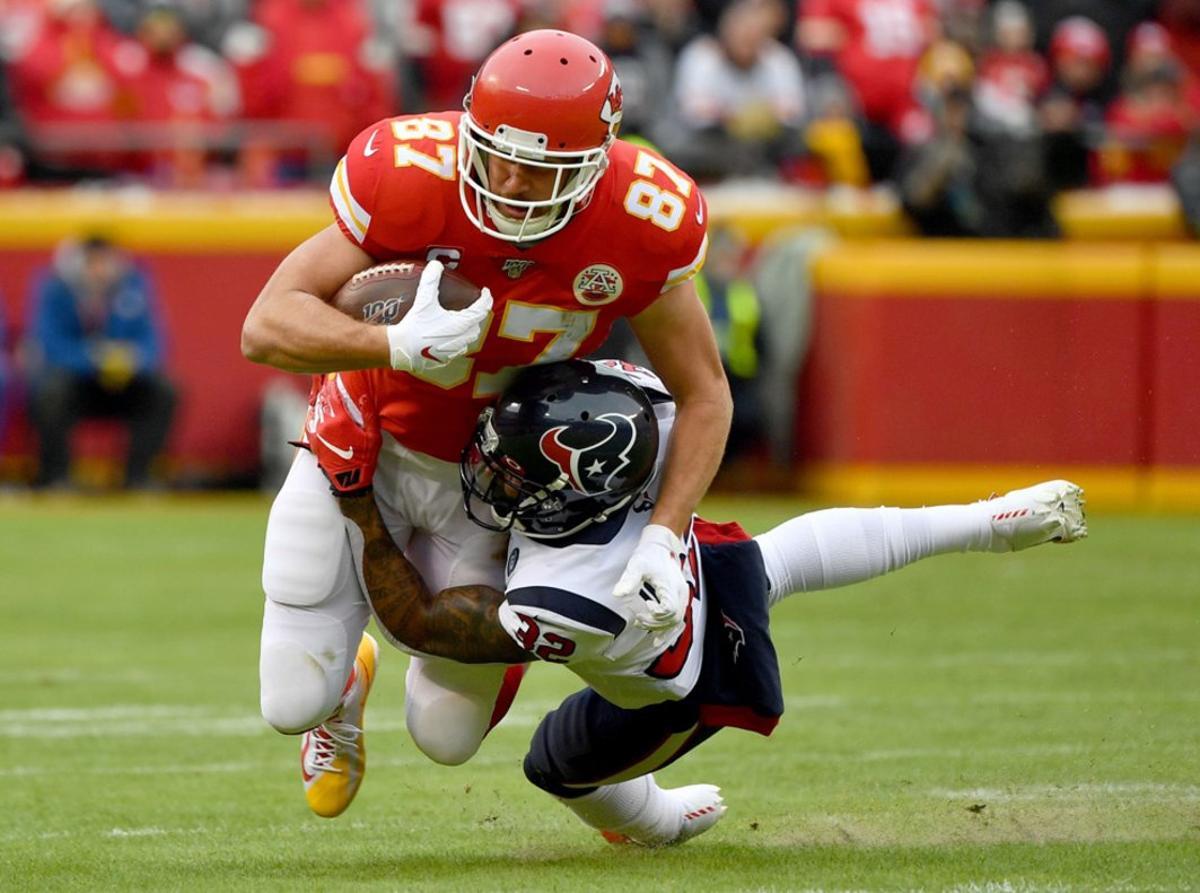 Travis Kelce # 87 de los Kansas City Chiefs es abordado por Lonnie Johnson # 32 de los Houston Texans durante el partido de desempate divisional de la AFC en el Arrowhead Stadium.