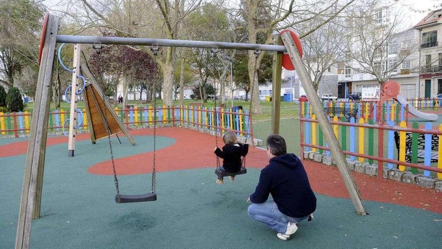 Un padre columpia a su hijo en un parque infantil.  // Noe Parga